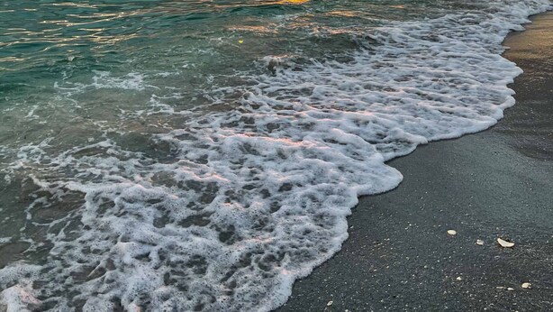 A beach with waves gently lapping onto the shore, a sunset in the background, and a person in a kayak. - Brand new Private Home-Beach Nearby in SW Florida (Port Charlotte)