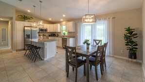 A modern kitchen with white cabinets, stainless steel appliances, and a central island with bar stools. - Brand new Private Home-Beach Nearby in SW Florida (Port Charlotte)