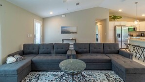 A living room with a sectional sofa, a glass coffee table, and a ceiling fan. - Brand new Private Home-Beach Nearby in SW Florida (Port Charlotte)
