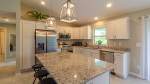 A modern kitchen with granite countertops, stainless steel appliances, and pendant lighting. - Brand new Private Home-Beach Nearby in SW Florida (Port Charlotte)