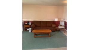 A living room with a brown sofa, a wooden coffee table, a lamp, and a small side table. - Historical King George Inn 1 (Niagara-on-the-Lake)
