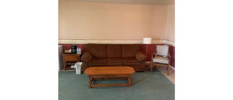 A living room with a brown sofa, a wooden coffee table, a lamp, and a small side table.