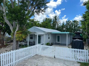 A single-story house with a white exterior and a green roof, surrounded by a white picket fence. - New 2/1 Remodeled Cozy Home in Tavernier Key (Tavernier)