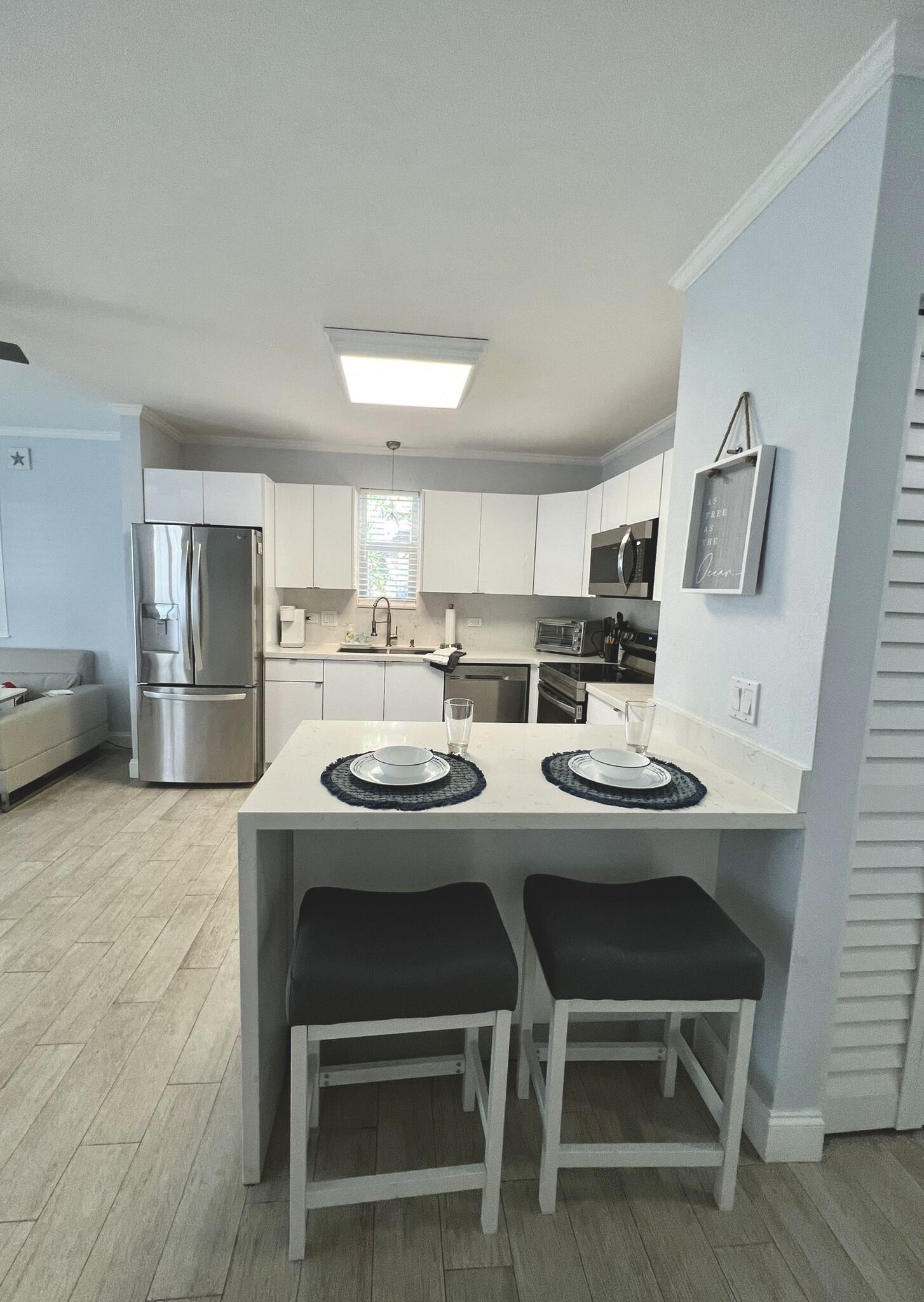 A modern kitchen with white cabinets, stainless steel appliances, and a central island with stools.