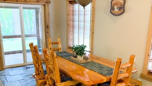 Una mesa de madera para comer con seis sillas, un camino de mesa tejido y una lámpara colgante.