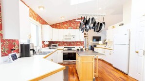 A modern kitchen with white cabinets, a wooden countertop, and a central island. - Crystal Lake Ridge, 30-day rental, community pool (Benzonia)