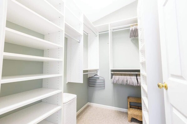 A walk-in closet with open shelving, a hanging rack, and a small bench.