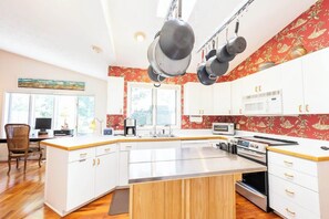 A modern kitchen with white cabinets, a central island, and a red patterned backsplash.