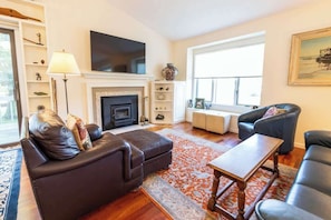 A living room with a fireplace, leather sofas, a coffee table, and a large window.