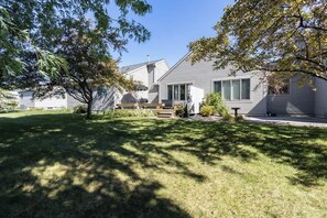 A residential house with a front yard, a wooden deck, and a small garden area. - Crystal Lake Ridge, 30-day rental, community pool (Benzonia)