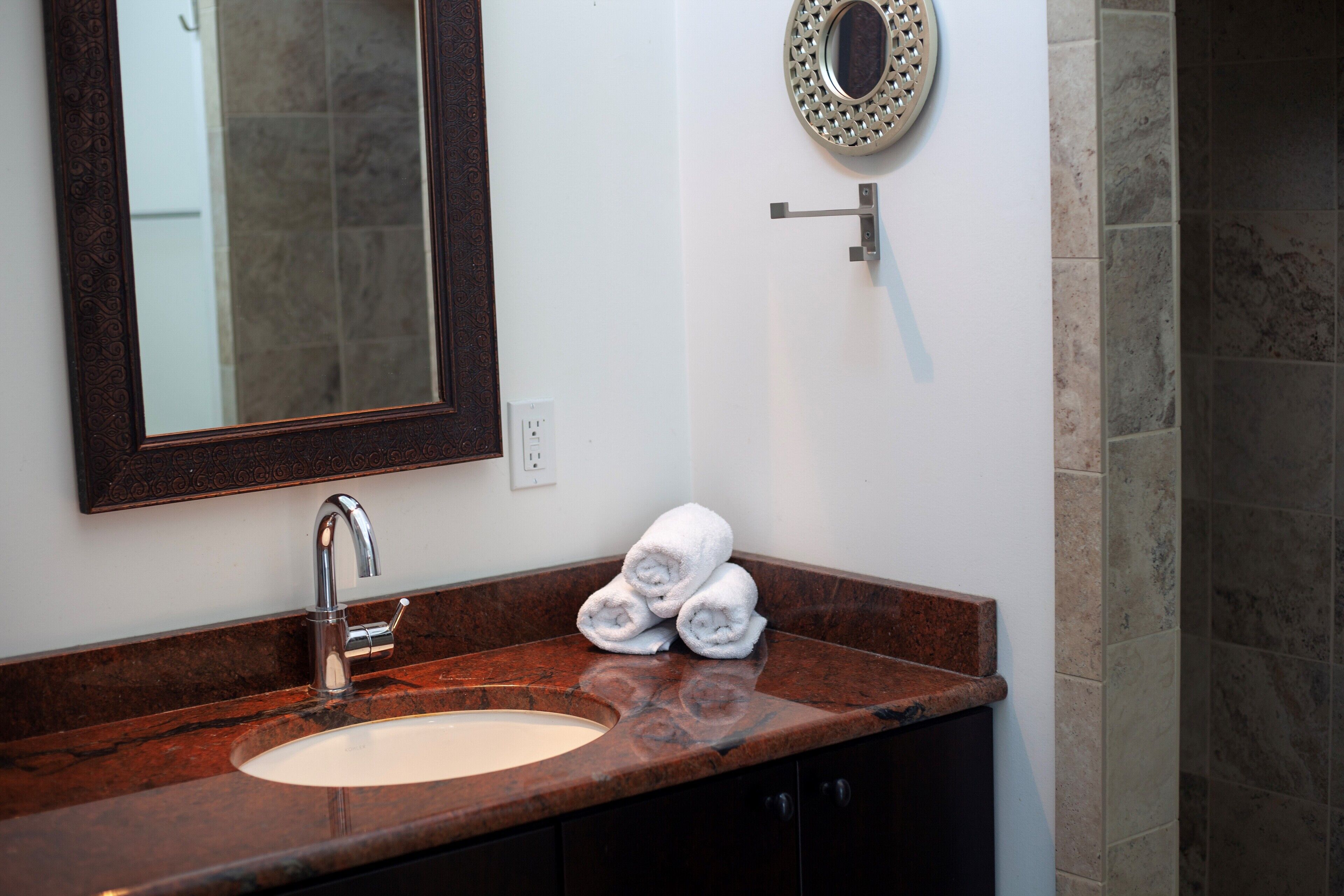 A bathroom with a marble sink, a mirror, and a towel rack.