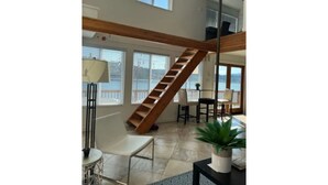 A spacious living area with a wooden staircase, large windows, and a view of the outdoors. - Lakefront & private beach  (Redmond)