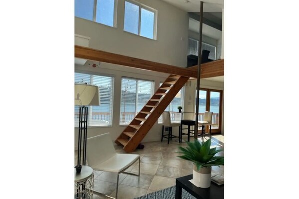 A spacious living area with a wooden staircase, large windows, and a view of the outdoors. - Lakefront & private beach (Redmond)