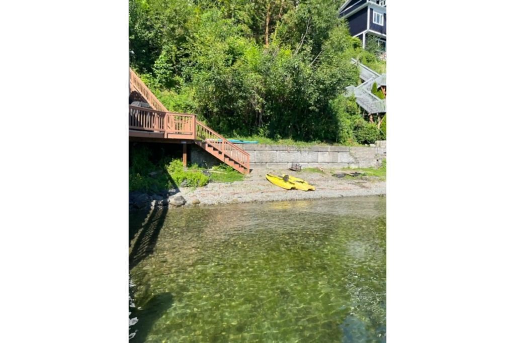 A wooden bridge leading to a riverbank with a kayak on the ground.
