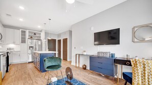 A modern kitchen with white cabinets, a built-in fridge, and a dining area with a blue chair and a decorative rug. - Modern Luxury ☞ King Bed ☞ 1BR in Plaza Midwood (Charlotte)
