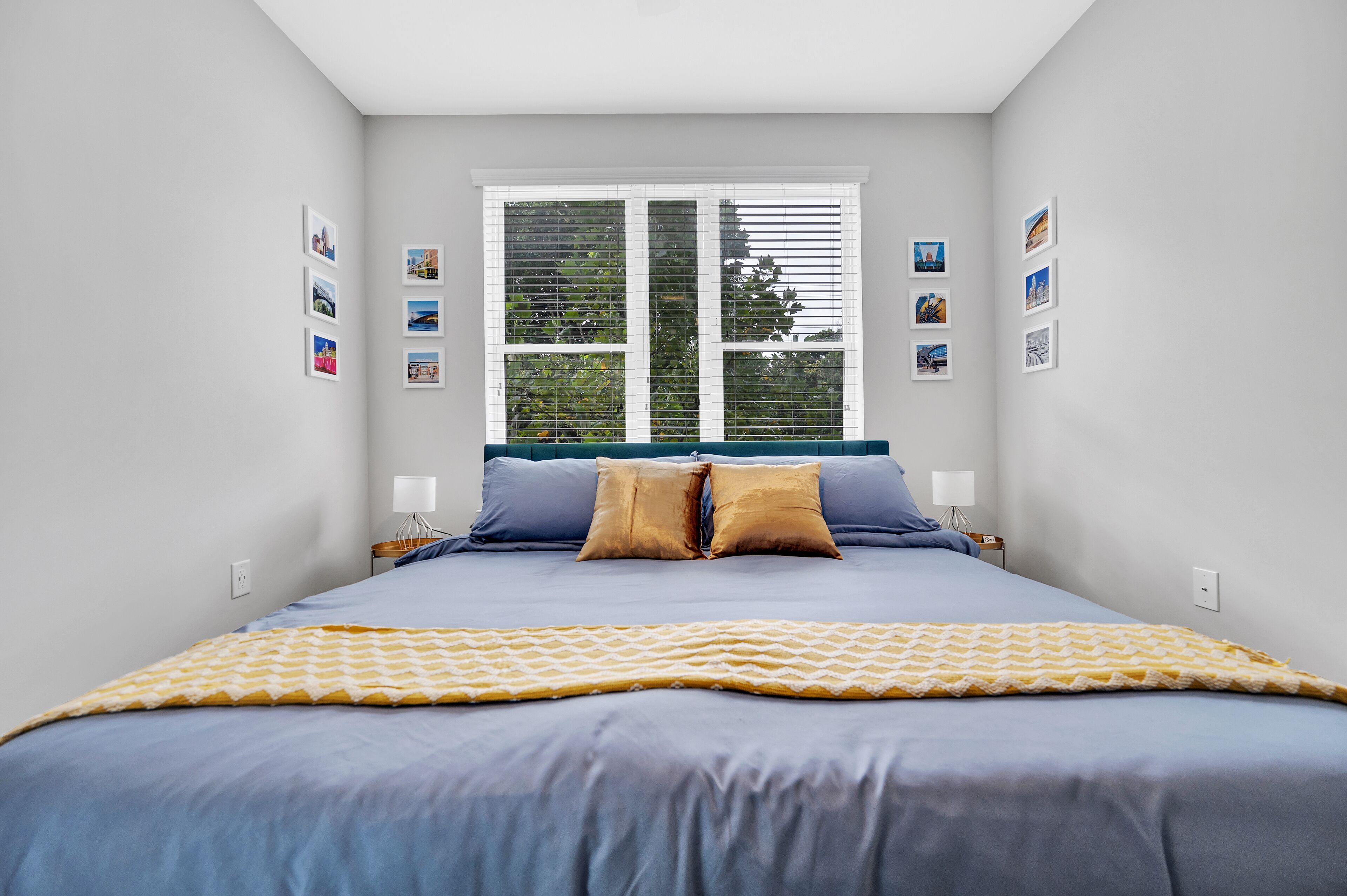 Une chambre à coucher avec un lit, des oreillers, une fenêtre et des tableaux accrochés au mur.