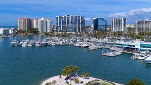A marina with numerous boats docked, surrounded by high-rise buildings and a sandy beach area with trees. - Designer Coastal Pool + Game Room home close to Siesta and downtown (Sarasota)