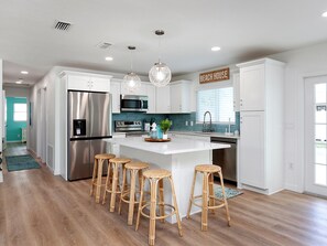A modern kitchen with white cabinets, stainless steel appliances, and a central island with bar stools.