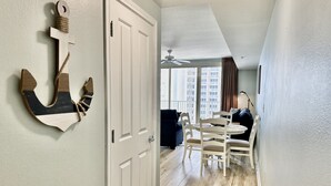 Un soggiorno moderno con zona pranzo, un'ampia finestra vista edifici e una ventola a soffitto.