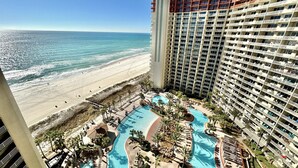 Un hotel moderno con vista sulla spiaggia, area piscina con diverse sezioni e spiaggia sullo sfondo.