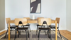 A dining area with a wooden table and four chairs, a white vase on the table, and a framed abstract painting on the wall. - Lovely Leopoldstadt 2BR w/ Elevator & city view, nr Danube, by Blueground (Vienna)