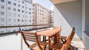 A balcony with a wooden table and chairs, overlooking a row of buildings. - Lovely Leopoldstadt 2BR w/ Elevator & city view, nr Danube, by Blueground (Vienna)