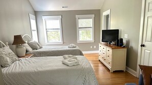 Un dormitorio con dos camas, televisión, cómoda y ventana.