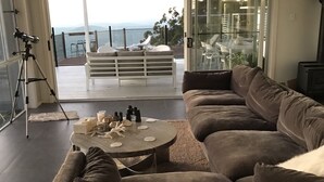 A modern living room with a large sectional sofa, a round coffee table, and a balcony with outdoor seating. - Views from Stradbroke to Tweed Heads (Wongawallan)