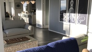 A modern living room with a sofa, a coffee table, and a blue blanket. There is a wooden sculpture on a shelf. - Views from Stradbroke to Tweed Heads (Wongawallan)