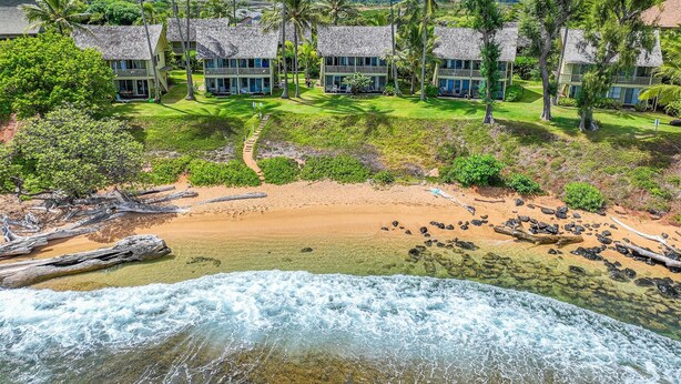 Ein Strandresort mit mehreren bungalowsartigen Gebäuden, einem Sandstrand und einem Wasserfall.