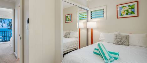 Habitación de hotel con cama, espejo, ventana con vista al mar y puerta que da a un balcón.