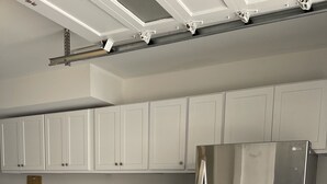 Eine kompakte Küche mit weißen Schränken, einem Edelstahlkühlschrank, einer Mikrowelle und einer Waschmaschine.