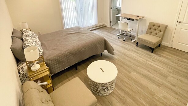 Ein modernes Schlafzimmer mit einem großen Bett, einem kleinen runden Tisch, einem Sessel und einem Schreibtisch.
