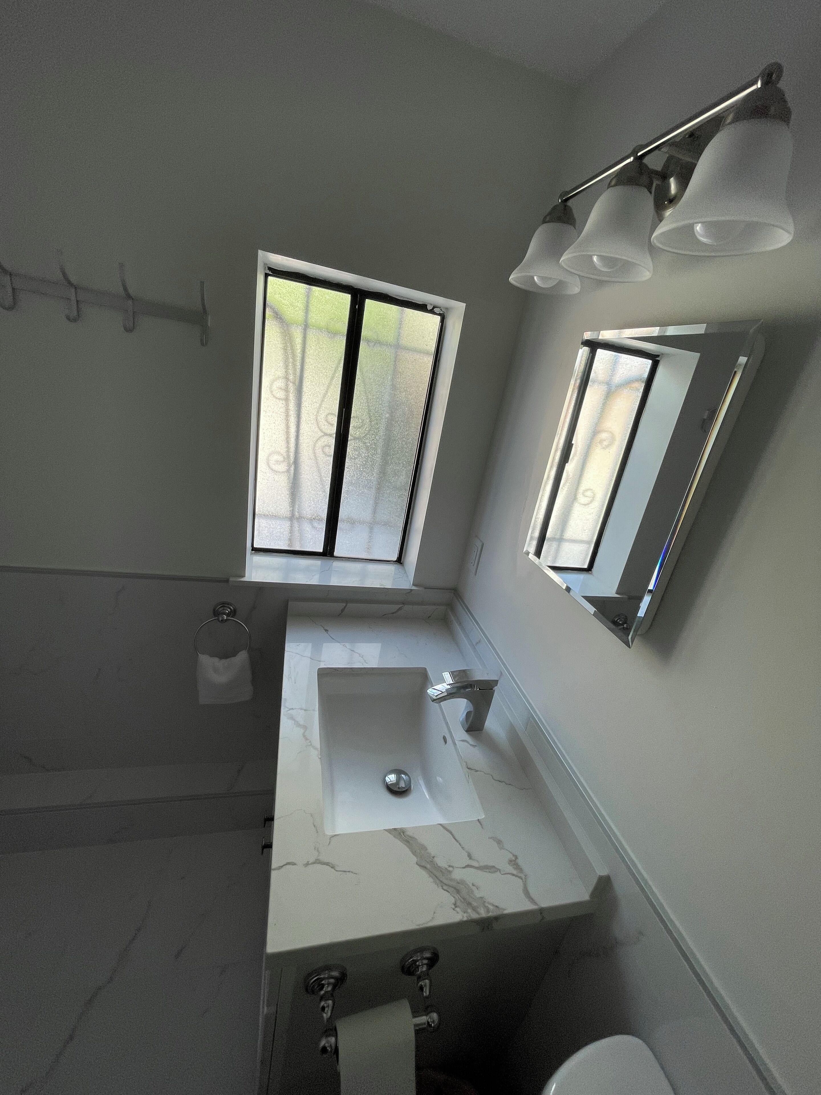 Un baño moderno con un ventanal grande, un lavabo y un espejo.