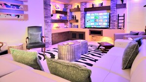 A modern living room with a flat-screen TV, a stone accent wall, and a zebra-patterned rug.
