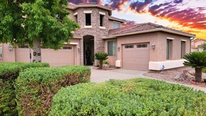 A two-story house with a stone facade, a garage, and a well-maintained garden.