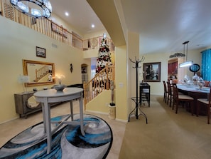 Un espacio habitable amplio con una mesa de comedor, una escalera decorada con un árbol de Navidad y un espejo grande en la pared.