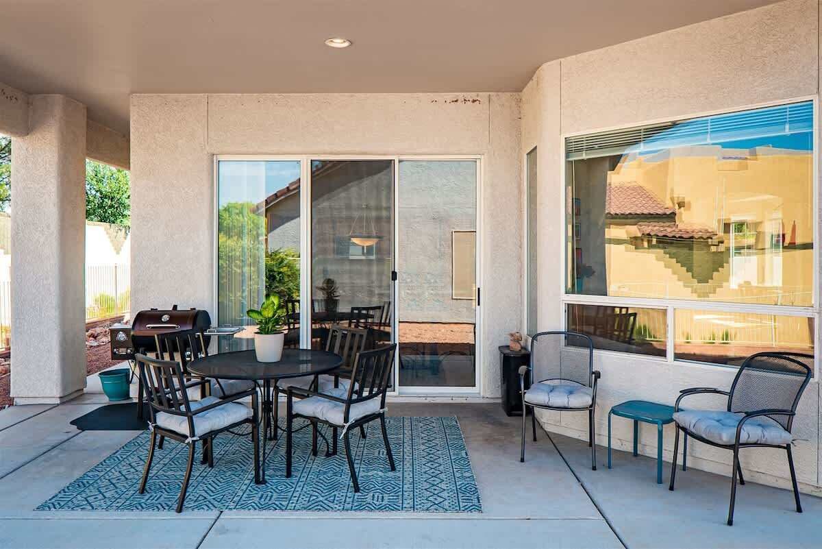 Une terrasse extérieure avec une table ronde, des chaises, un barbecue et une plante en pot.