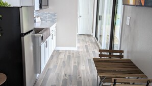 Una cocina moderna con armarios blancos, un refrigerador negro y una mesa de comedor de madera con bancos.