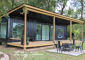 A modern, compact cabin with a wooden deck, large windows, and outdoor seating. - The Cozy Container, Country Living, Modern Design (New Waverly)