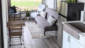 Una cocina moderna con un sofá gris, una mesa de comedor y un televisor montado en la pared.