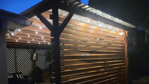 Un espacio de estar al aire libre cubierto, con listones de madera e iluminación con guirnaldas.
