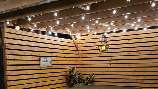 Un área de estar interior acogedora con listones de madera en las paredes, un jacuzzi y luces colgantes.