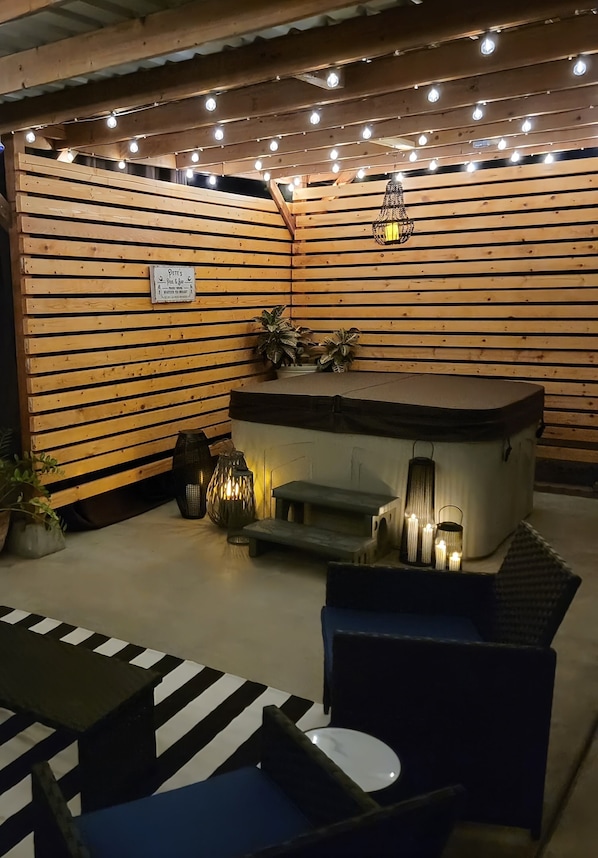 Un espace de détente intérieur accueillant, avec des lambris en bois aux murs, un jacuzzi et des guirlandes lumineuses.