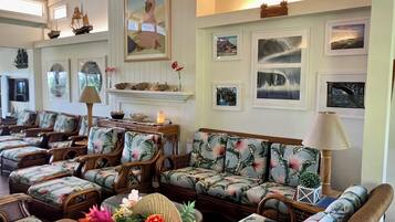 A spacious lounge area with multiple seating options, including sofas and chairs, arranged around a central fireplace.
