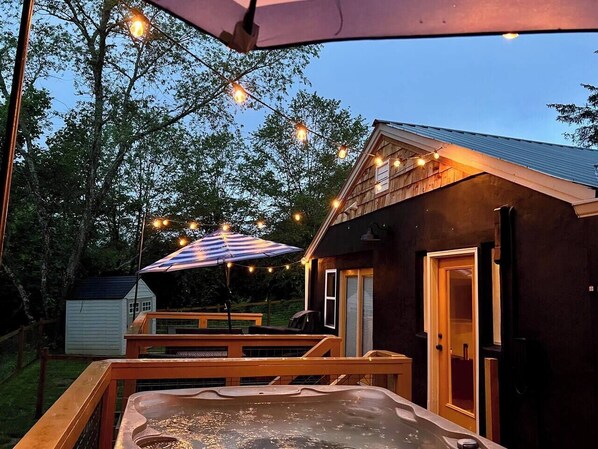 A hot tub on a wooden deck with a covered area and string lights.