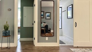 A hallway with a sliding door, a mirror, and a small table with a plant.