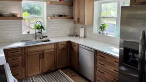 A modern kitchen with wooden cabinets, white countertops, and a built-in dishwasher.