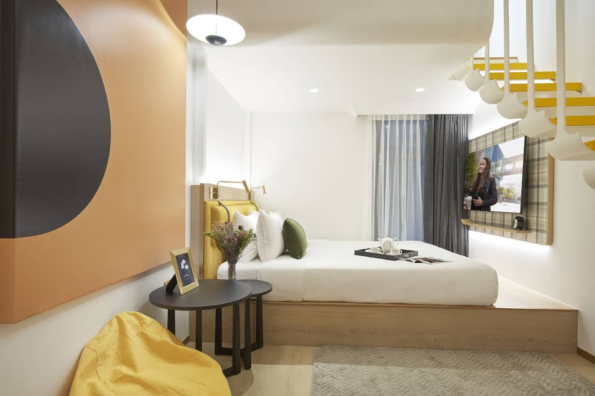Ein modernes Hotelzimmer mit Bett, Nachttisch und einer kleinen Sitzecke.