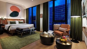 A modern hotel room with a large bed, a sitting area with a coffee table, and a view of a cityscape through large windows. - Citadines Connect City Centre Singapore (Singapore)